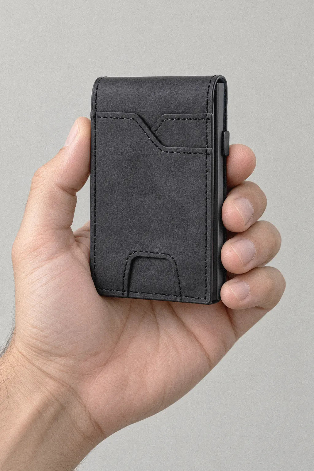 The closed wallet held in a hand for scale